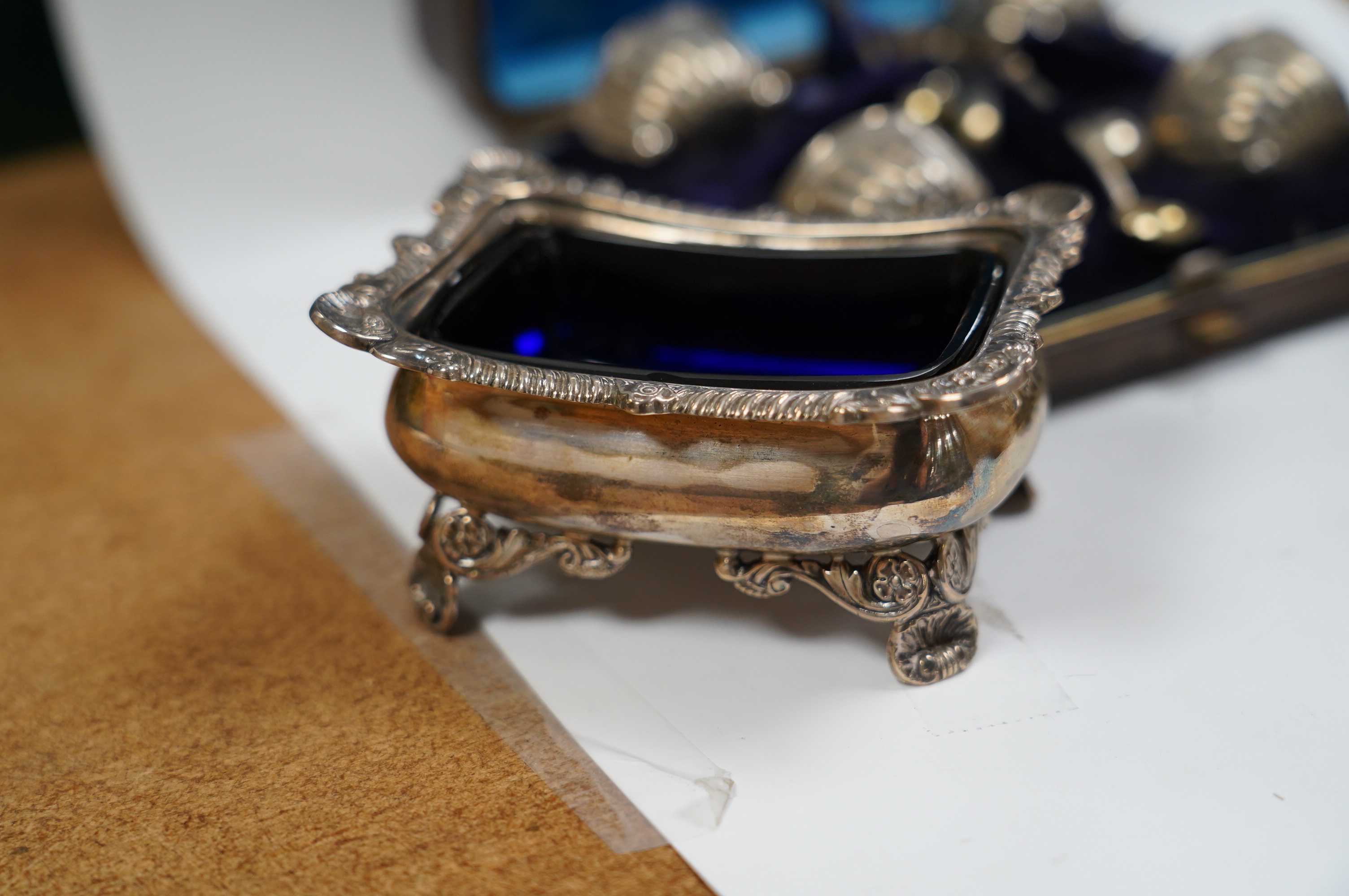 A pair of late Victorian silver rectangular salts, Hawksworth, Eyre & Co, London, 1897, 91mm with blue glass liners and a cased set of four Victorian silver tub salts with spoons. Condition - fair